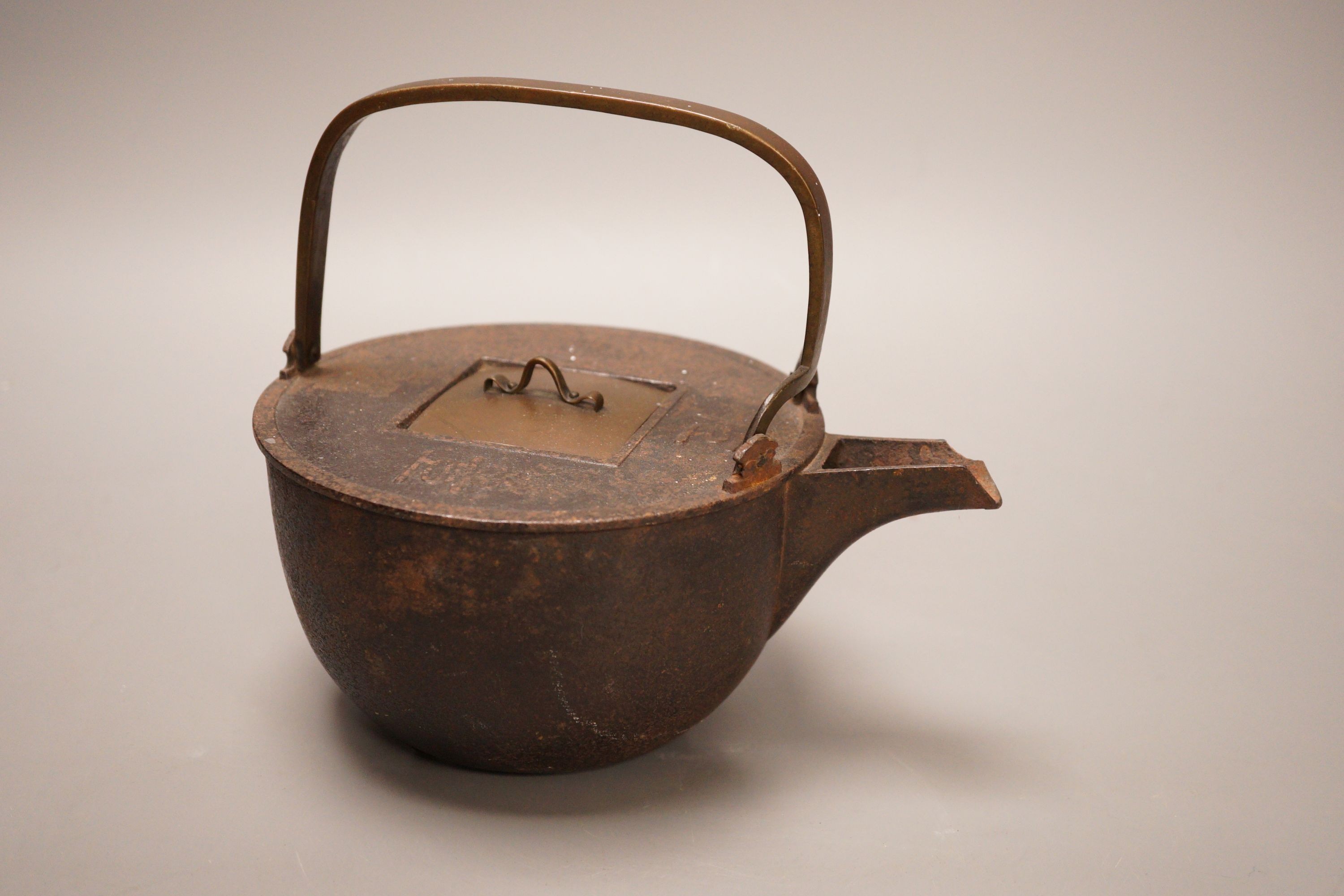 A Japanese cast iron and bronze teapot on tripod stand, inscribed, 19cm wide including spout